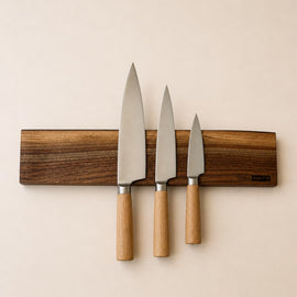 20 inch live edge walnut magnetic knife holder with three chef knives mounted on a neutral background
