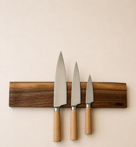 20 inch live edge walnut magnetic knife holder with three chef knives mounted on a neutral background