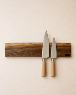 20 inch live edge walnut magnetic knife holder with three chef knives mounted on a neutral background