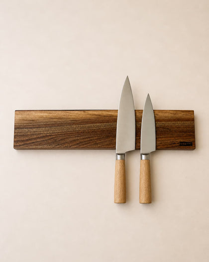 20 inch live edge walnut magnetic knife holder with three chef knives mounted on a neutral background