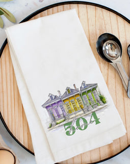 504 Home flour sack kitchen towel with illustrated New Orleans houses in purple, gold, and green on a white cotton towel.