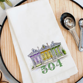 504 Home flour sack kitchen towel with illustrated New Orleans houses in purple, gold, and green on a white cotton towel.