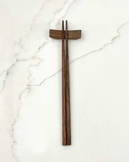 9-inch walnut chopsticks resting on a matching walnut chopstick rest, photographed on a white background.