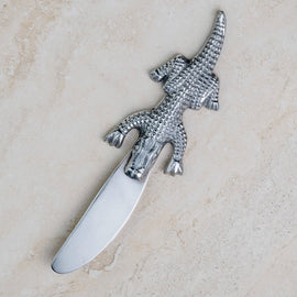 Alligator-handle stainless steel spreader on light stone background.