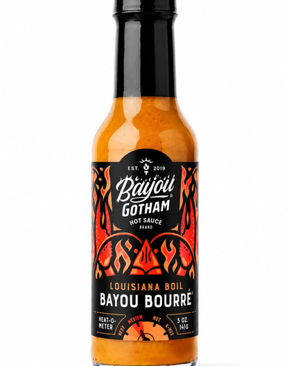 A 5 oz bottle of Bayou Gotham Louisiana Boil Bayou Bourré hot sauce, featuring an orange-red sauce inside a clear glass bottle with a black cap and a black label with red and white graphics.