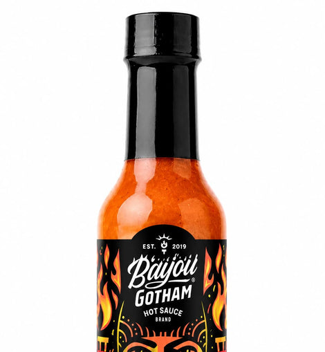 A bottle of Bayou Gotham Caribbean Creole Flambeau Fiya hot sauce, featuring a black cap and a black label with red, orange, and yellow graphics, set against a plain white background.