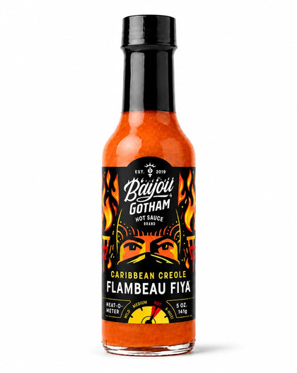 A bottle of Bayou Gotham Caribbean Creole Flambeau Fiya hot sauce, featuring a black cap and a black label with orange and yellow graphics, set against a plain white background.