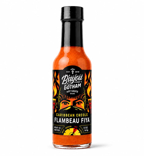 A bottle of Bayou Gotham Caribbean Creole Flambeau Fiya hot sauce, featuring a black cap and a black label with orange and yellow graphics, set against a plain white background.