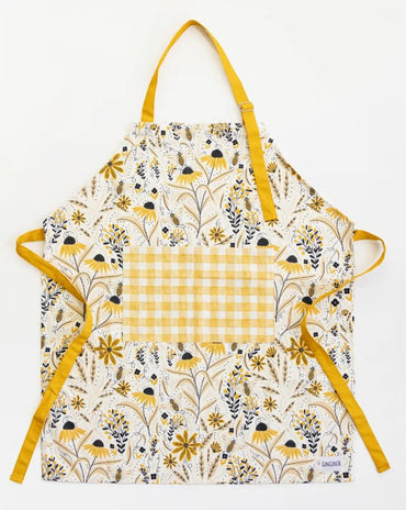 a cream kitchen apron with yellow wildflowers, honeybee illustrations, yellow straps, and a coordinating yellow gingham pocket.