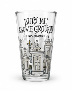A clear pint glass featuring a black and white graphic illustration of New Orleans cemeteries and the text 'BURY ME ABOVE GROUND IN NEW ORLEANS' on a white background.