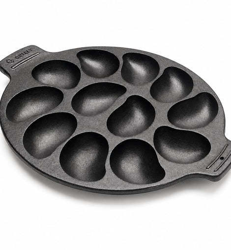 A black cast iron 10 oyster pan with teardrop-shaped cavities, shown on a clean white background. 