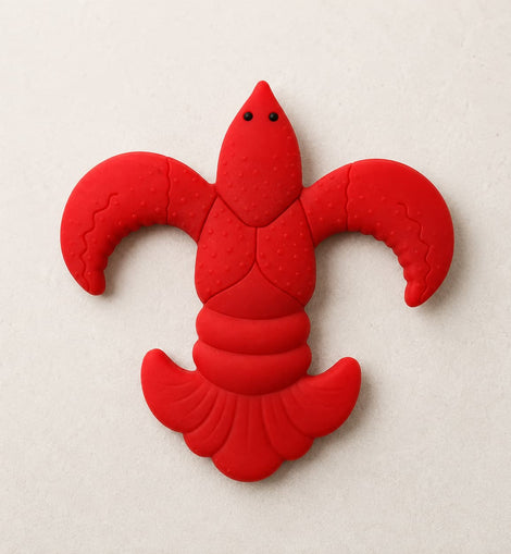 A bright red lcrawfish baby teether shown on a light beige textured background.