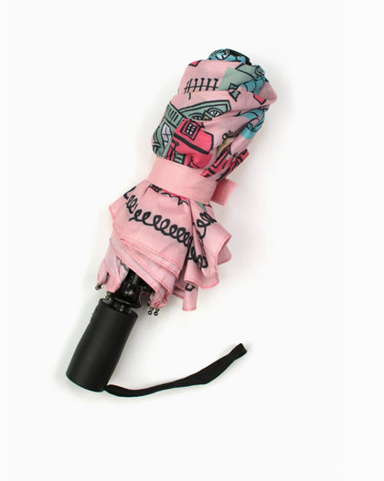 Pink travel umbrella featuring illustrated New Orleans Creole cottages and architectural homes with wrist strap displayed closed.