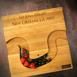 Handmade cherry Crescent City Board with curved edge holding crackers and olives, engraved with address