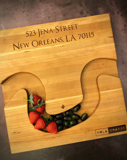 Handmade cherry Crescent City Board with curved edge holding crackers and olives, engraved with address
