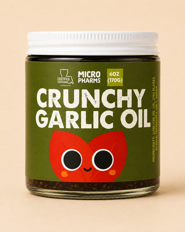 A jar of Micropharmes Crunchy Garlic Oil with a dark olive green label, white cap, and a red cartoon garlic bulb graphic, set against a solid beige background.
