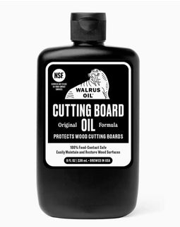 A black plastic bottle of Walrus Oil Cutting Board Oil with a black cap and a white and black label, shown on a light gray background.