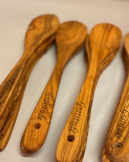 12-inch hand-carved olive wood spoon with rich grain pattern on a white background with engraving. 