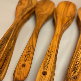 12-inch hand-carved olive wood spoon with rich grain pattern on a white background with engraving. 