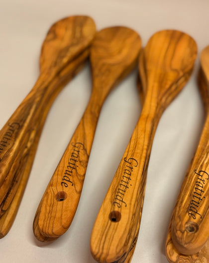 12-inch hand-carved olive wood spoon with rich grain pattern on a white background with engraving. 