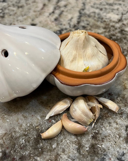 Ceramic garlic keeper shaped like a garlic bulb with small ventilation holes, designed to keep garlic fresh on the kitchen counter.