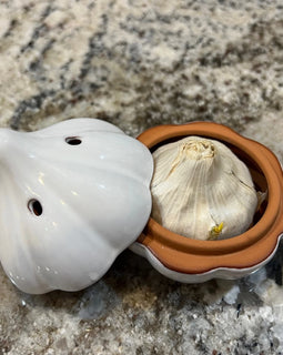 Ceramic garlic keeper shaped like a garlic bulb with small ventilation holes, designed to keep garlic fresh on the kitchen counter.