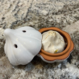 Ceramic garlic keeper shaped like a garlic bulb with small ventilation holes, designed to keep garlic fresh on the kitchen counter.