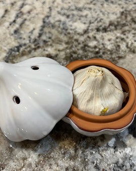 Ceramic garlic keeper shaped like a garlic bulb with small ventilation holes, designed to keep garlic fresh on the kitchen counter.