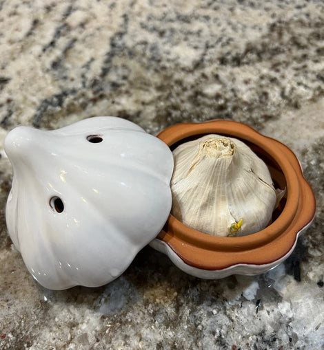 Ceramic garlic keeper shaped like a garlic bulb with small ventilation holes, designed to keep garlic fresh on the kitchen counter.