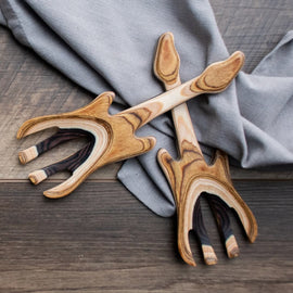 Guitar-shaped wooden salad hands made from layered hardwoods, displayed on a gray cloth atop a wooden surface.