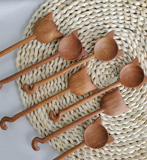 Hand-carved wooden cat stirring spoon with cat-shaped top and curved tail handle on a white background.