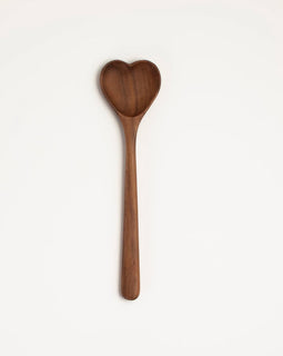Handcrafted heart-shaped walnut wooden spoon on white background.