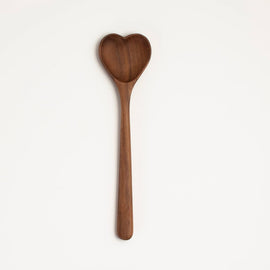 Handcrafted heart-shaped walnut wooden spoon on white background.