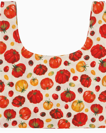 A reusable tote bag with a printed pattern of red, orange, and yellow tomatoes on an off-white background.