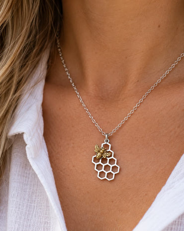 Silver honeycomb pendant necklace with a detailed bronze honeybee on a delicate silver chain.