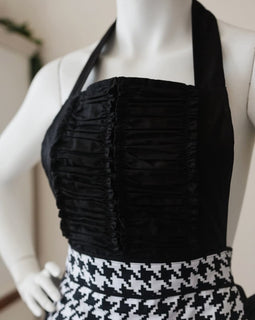 Black and white houndstooth apron with heart accent and ruffled hem.