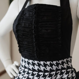 Black and white houndstooth apron with heart accent and ruffled hem.