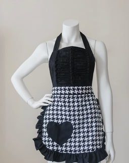 Black and white houndstooth apron with heart accent and ruffled hem.