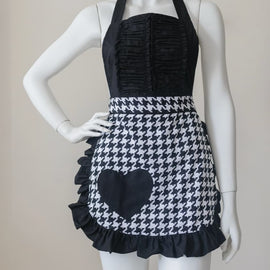Black and white houndstooth apron with heart accent and ruffled hem.