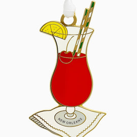 Enamel Hurricane cocktail ornament with lemon slice, cherry, striped straws, and ‘New Orleans’ napkin.