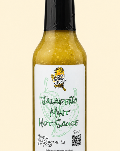 A bottle of Jalapeño Mint Hot Sauce by Smokey's Kitchen, featuring a white label with green text and a black cap, set against a solid pale beige background.