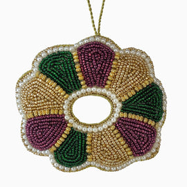 Hand-beaded King Cake ornament in purple, green, and gold with pearl accents and gold hanging loop.