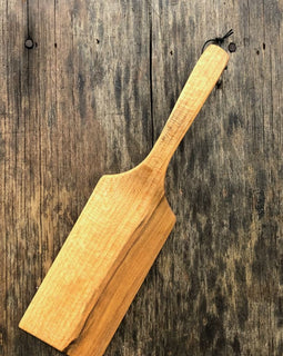 Handcrafted wooden flipper with long handle on rustic background