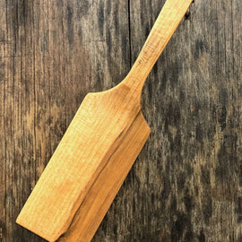 Handcrafted wooden flipper with long handle on rustic background