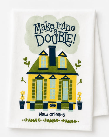 A white kitchen towel featuring a colorful illustration of a yellow house with green trim, the text 'Make mine DOUBLE!' in a cloud above, and 'New orleans' below.