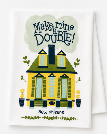 A white kitchen towel featuring a colorful illustration of a yellow house with green trim, the text 'Make mine DOUBLE!' in a cloud above, and 'New orleans' below.