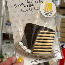 Maison Nola silicone baby teether in packaging held by a hand.