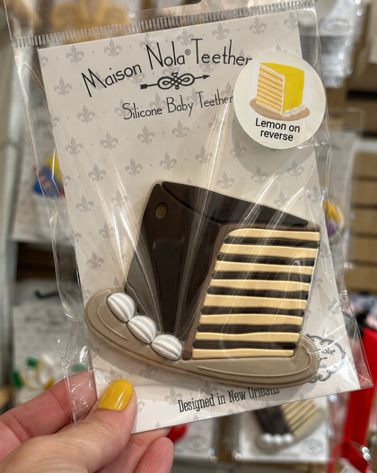 Maison Nola silicone baby teether in packaging held by a hand.