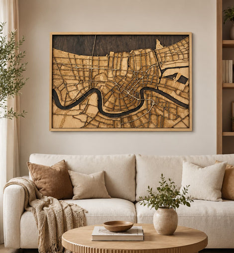 A large framed wooden map wall art piece depicting a winding river through a city, displayed above a cream sofa in a styled living room setting.