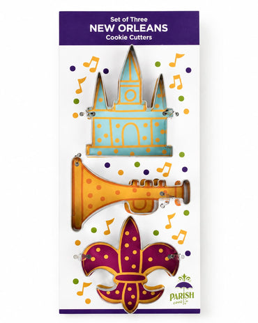 A package of three New Orleans-themed cookie cutters featuring a blue and gold cathedral, a gold trumpet, and a purple and gold fleur-de-lis, shown on a white background with a purple header.